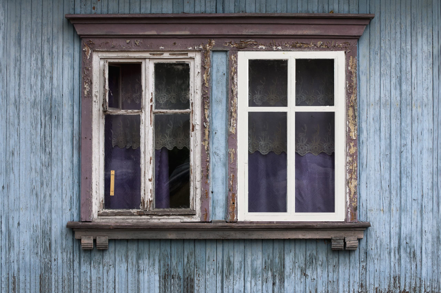 Vieille fenêtre en bois écaillée sur façade bleue dégradée